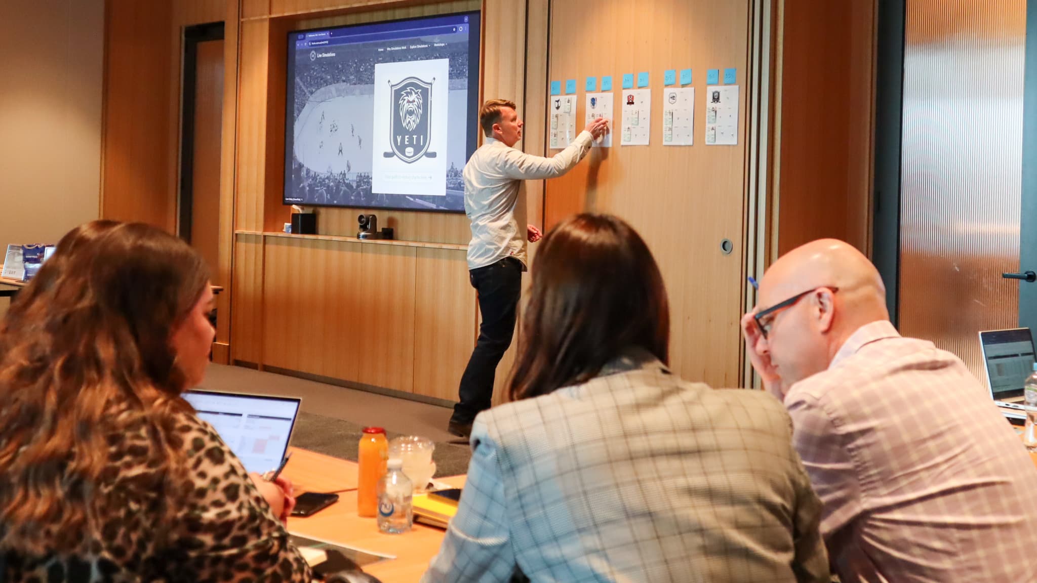 Liam reviewing player cards on the wall during a simulation debrief